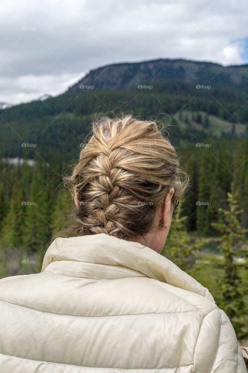 Blonde woman in French braid hairstyle taking in the breathtaking view of Canada's gorgeous Ricky Mountains near Banff Alberta 