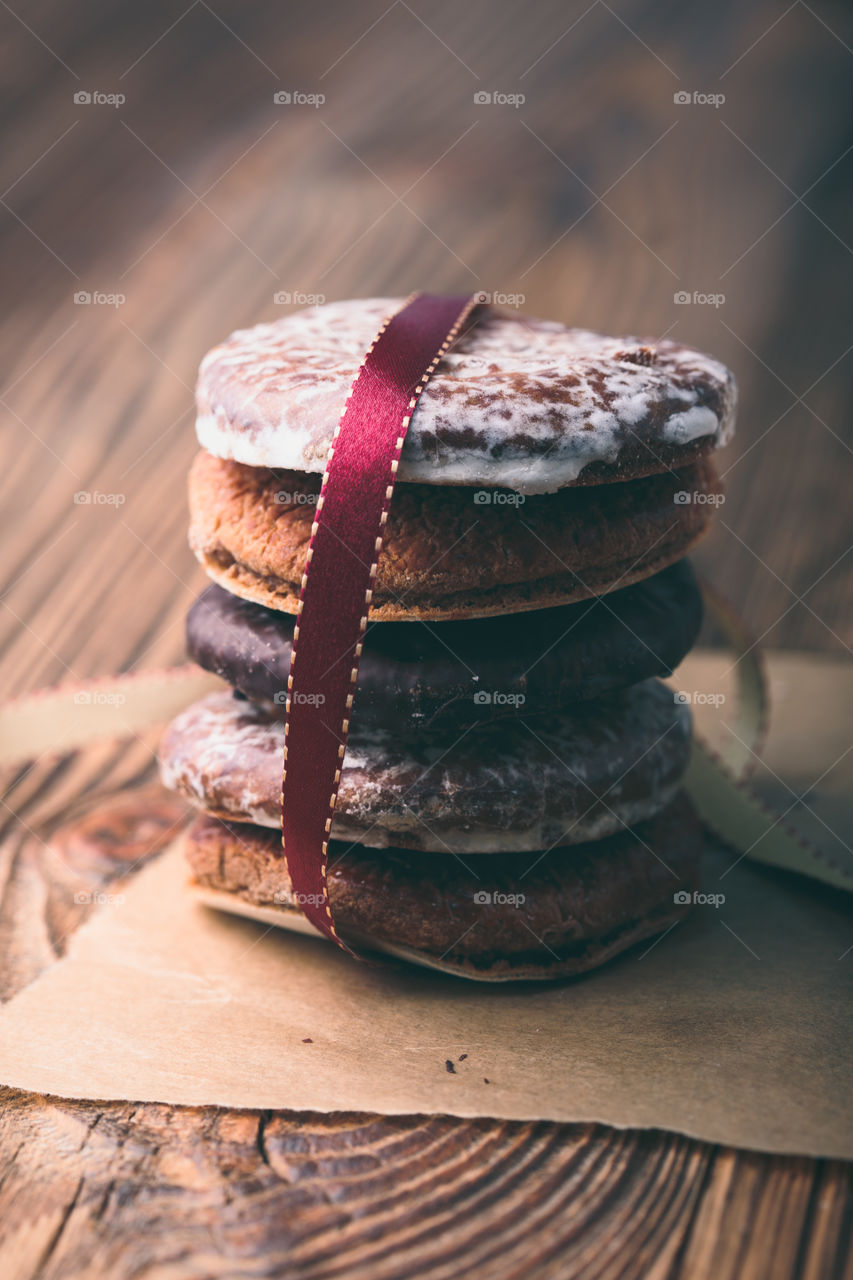 A few gingerbread cookies wrapped in red ribbon Happy Christmas on wooden table. Plain background. Portrait orientation