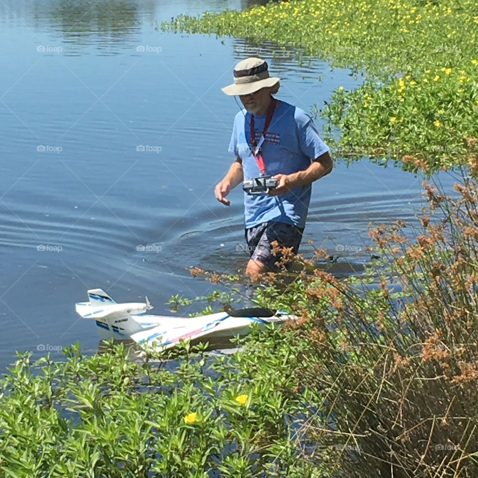 Man in water lake marsh river operating a remote control watercraft boat drone