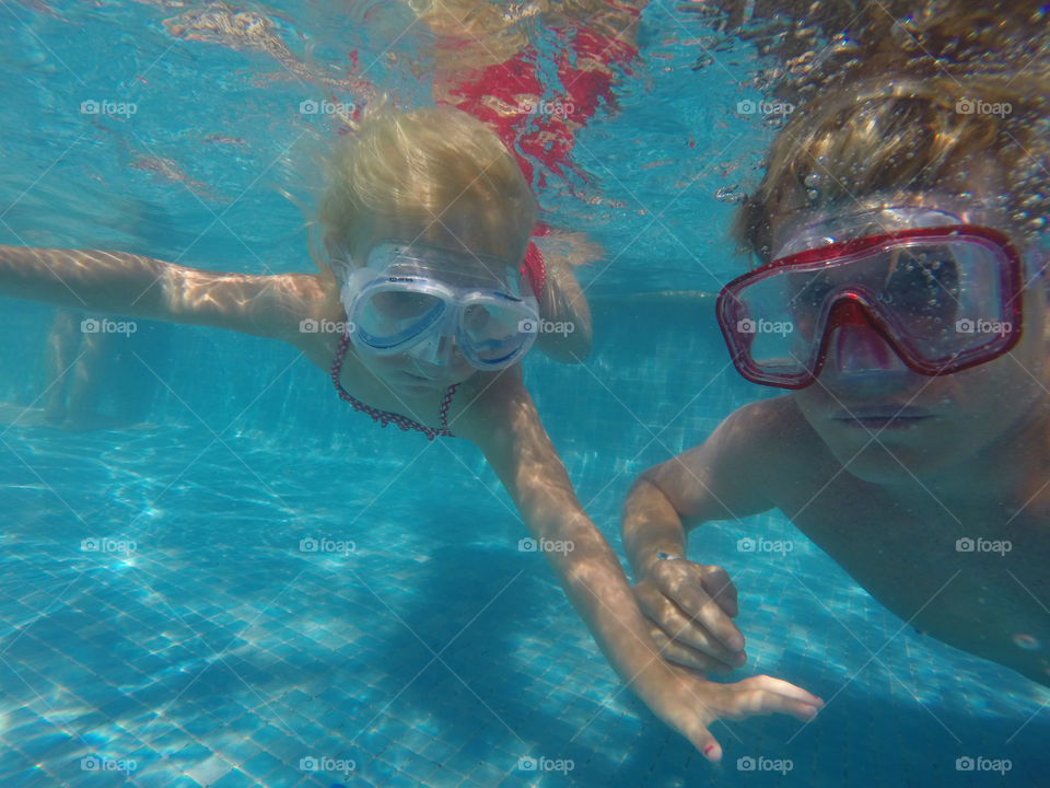 Little girl and her father diving underwater to get her toys in a swimming pool at Alcudia Pins in Alcudia on Majorca.