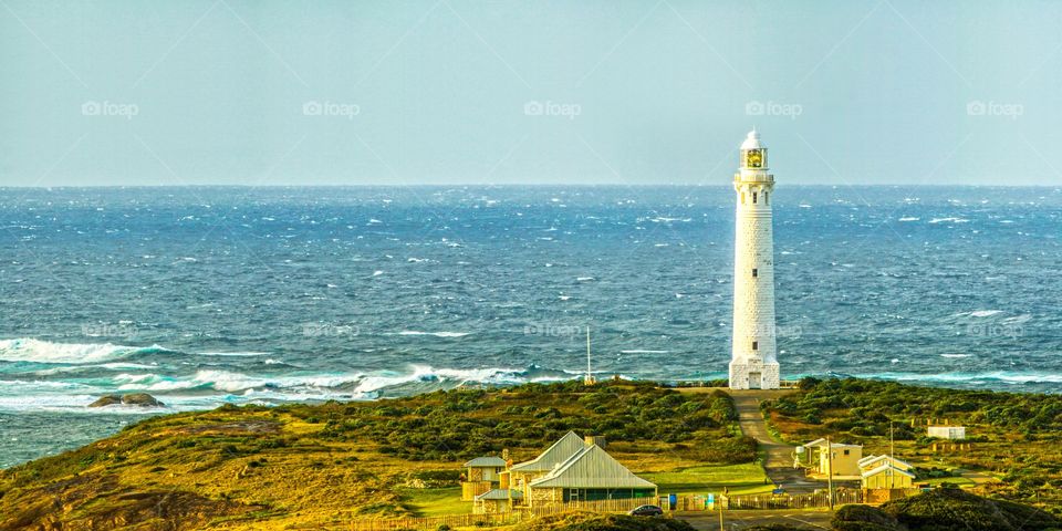 Cape Leeuwin lighthouse dwarfed by giant crashing waves on the coast at Augusta in South West Western Australia