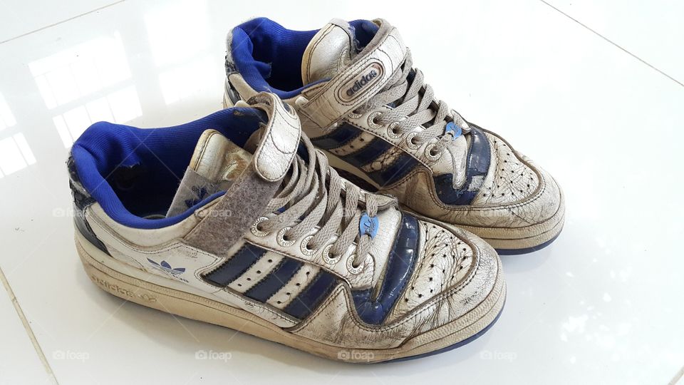 Dirty sport shoes. white and blue used adidas sneakers