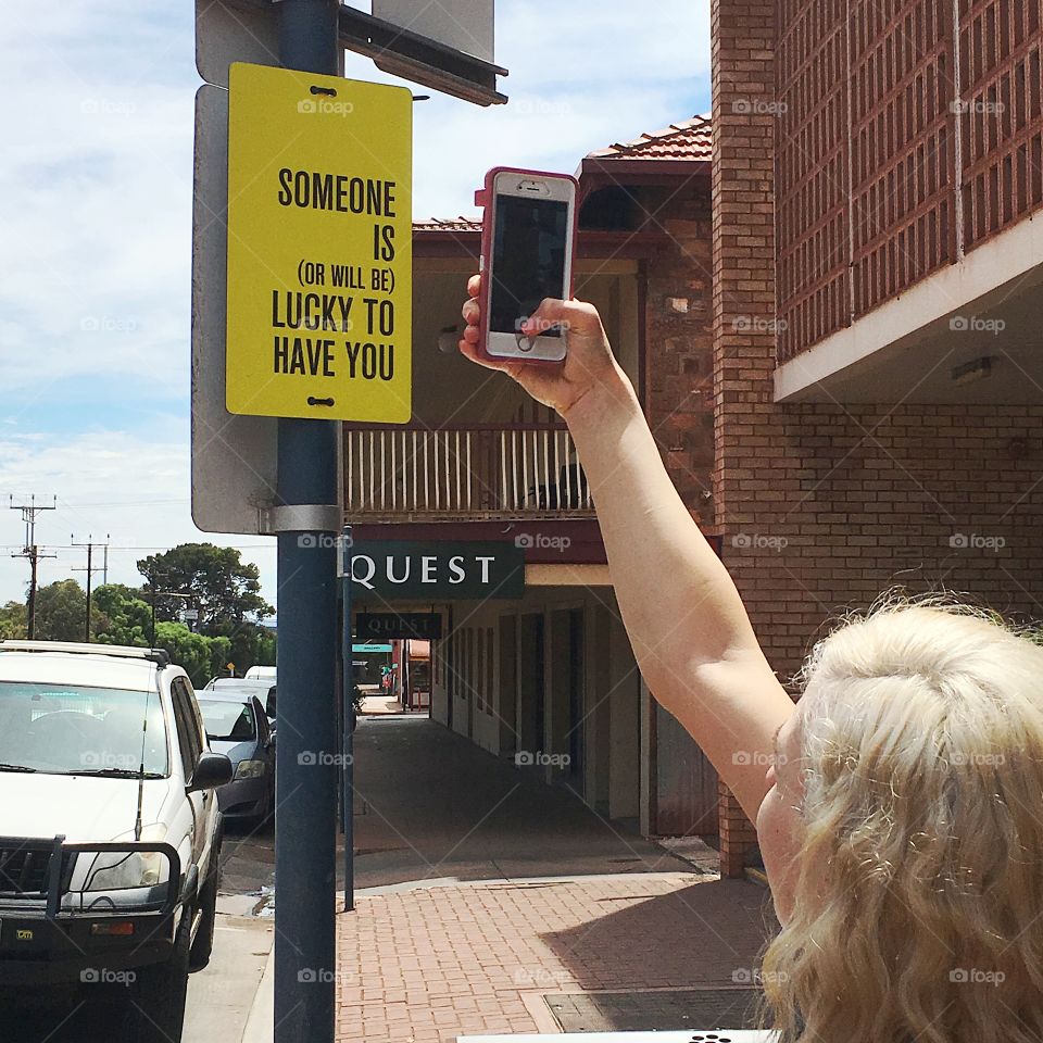 Woman holding mobile phone and photographing at street