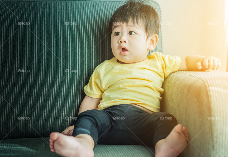 Cute baby siting on the sofa with sunrise