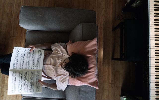 Boy reading music sheets in front of the piano