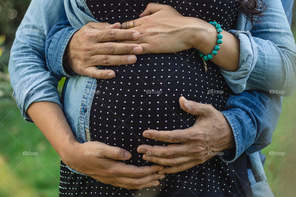 Hands of parents showing love to the future baby