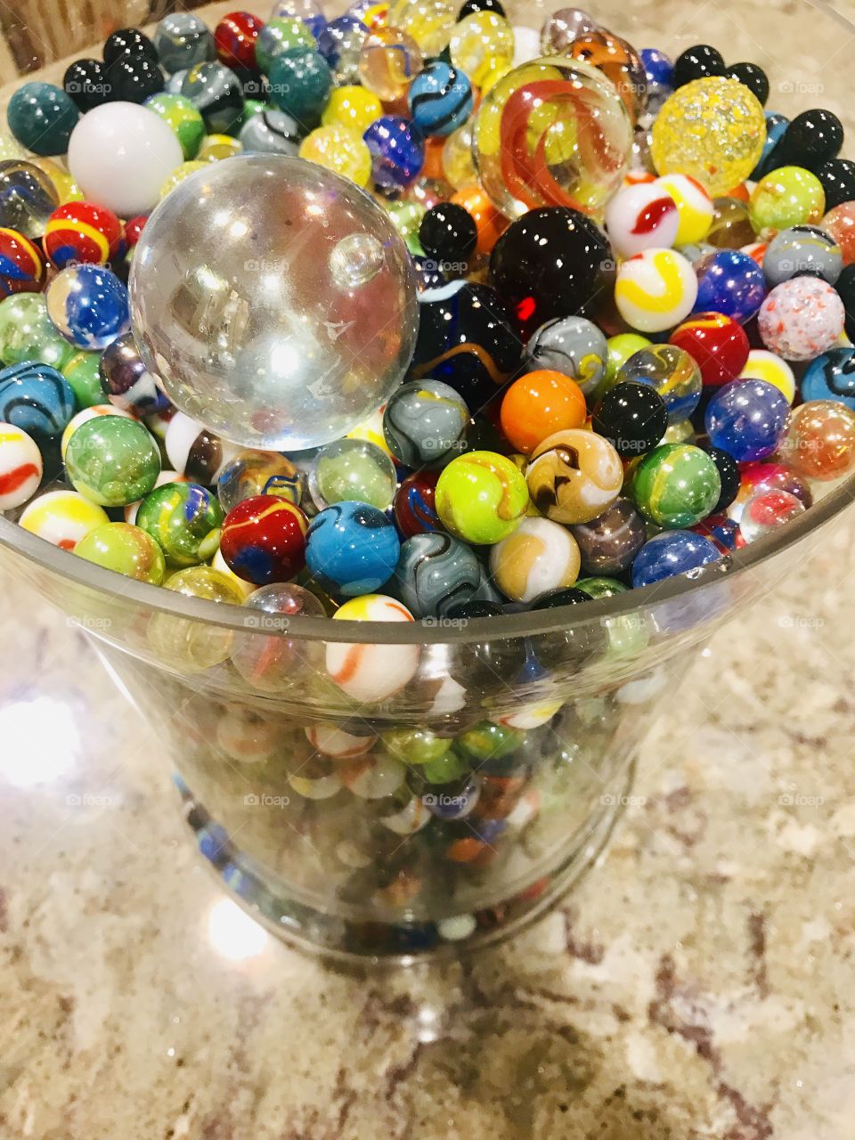 Beautiful very colorful photo of different sized marbles all displayed in large glass jar. 