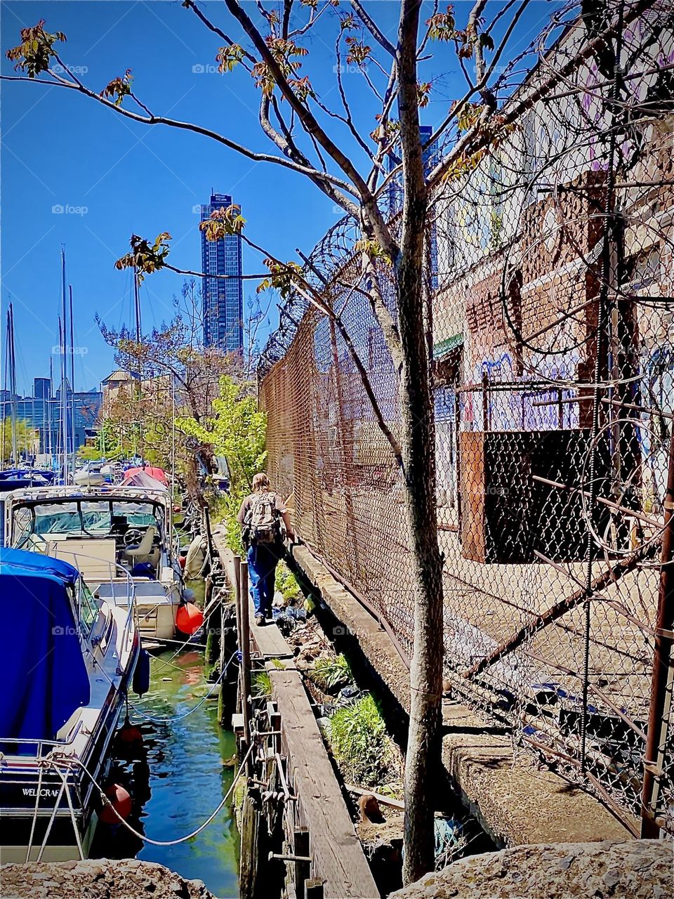 Timothy walking towards our boat, the „Salvation“ in the creek very carefully along the reinforced wooden planks by the wall on the shore. It’s a beautiful day in early May of 2022. Hypnotic Productions