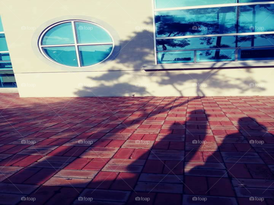 a shadow of a child walking while the mother  is sitting on the chair.