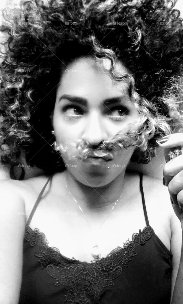 Portrait of a woman making moustache made of hair on face