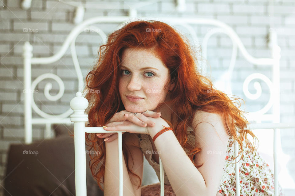 Portrait of beautiful young smiling redhead woman with freckles in the morning in her bad.