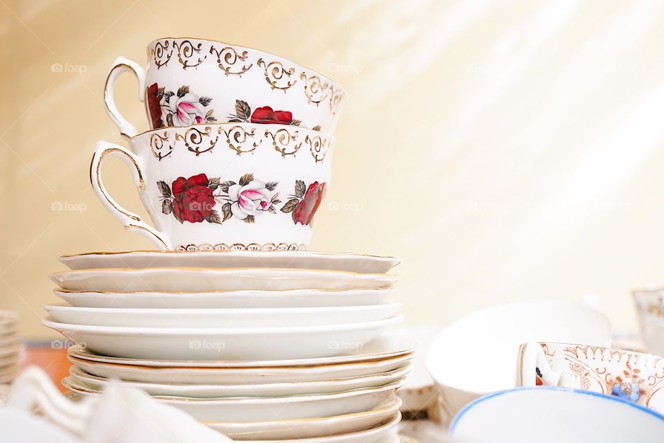 Vintage English porcelain teacups and saucers with rose and flowers pattern, selective focus.