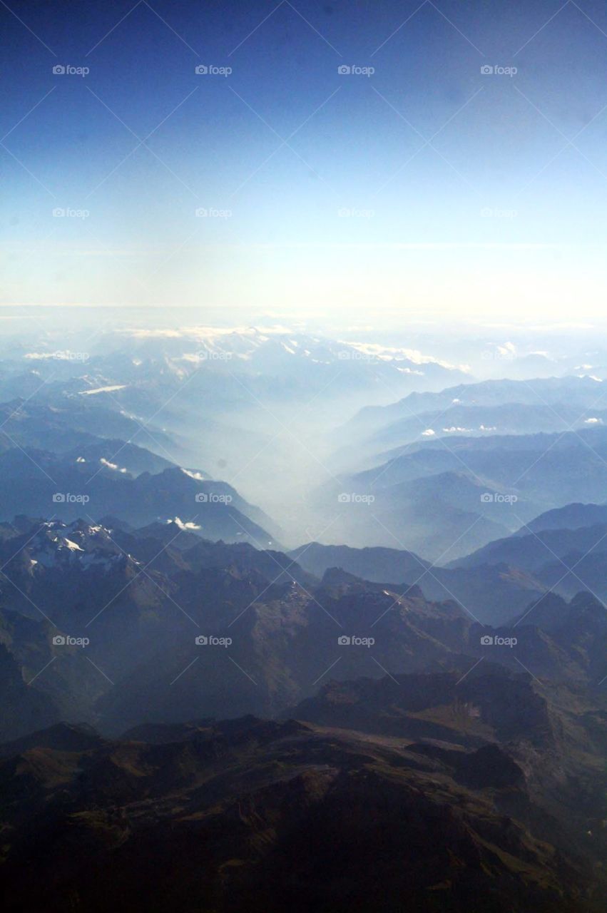 Clouds in the alps . View from my plane window on the way to Italy, flying over the alps, misty clouds pouring inbetween the mountains