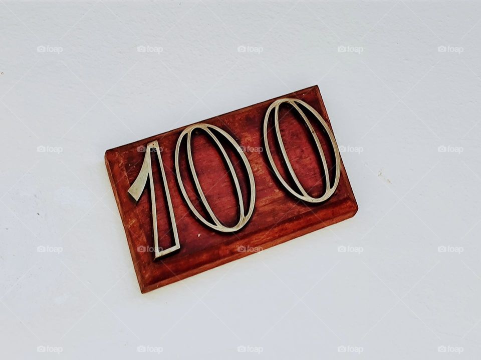 Number one hundred placed on a varnished wooden board