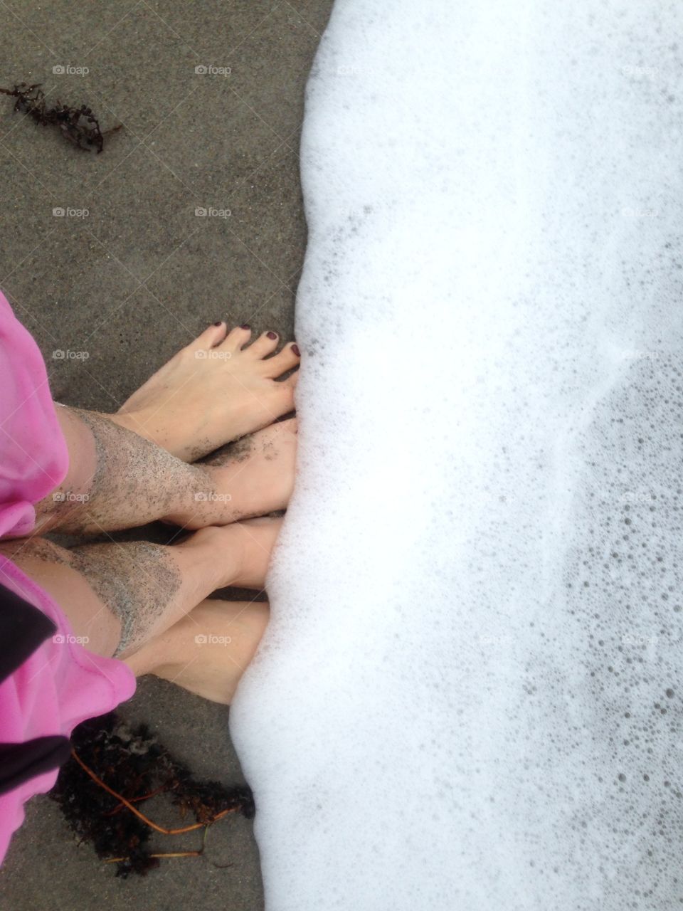 Mother and daughter feet in the waves at the beach 