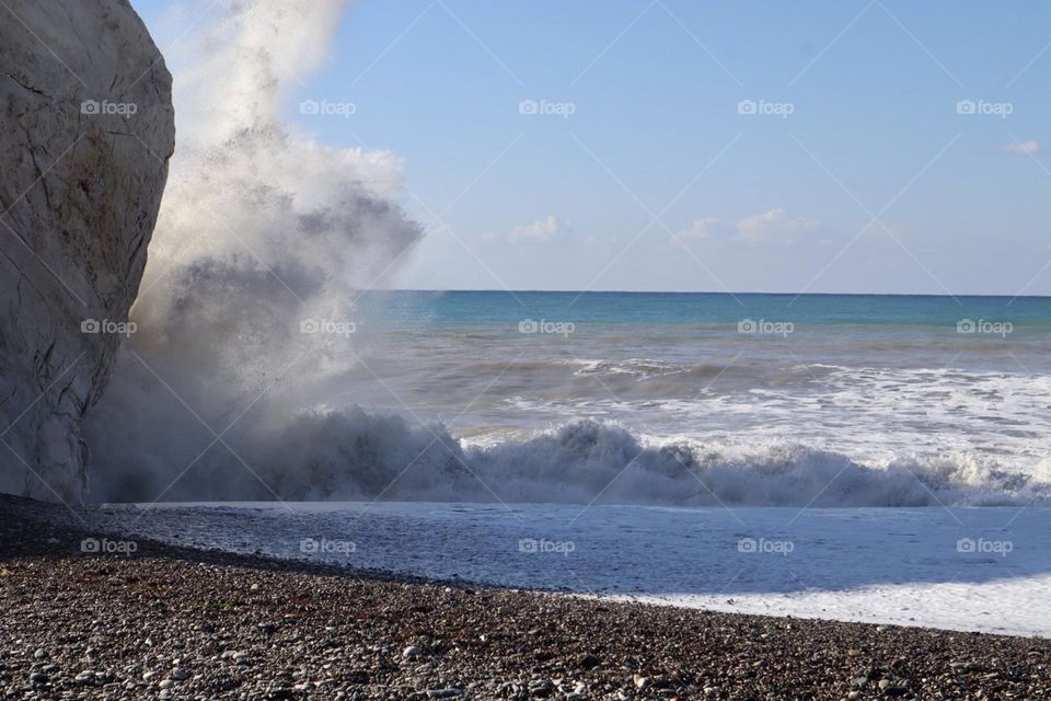 Waves crash over big rock on the beach