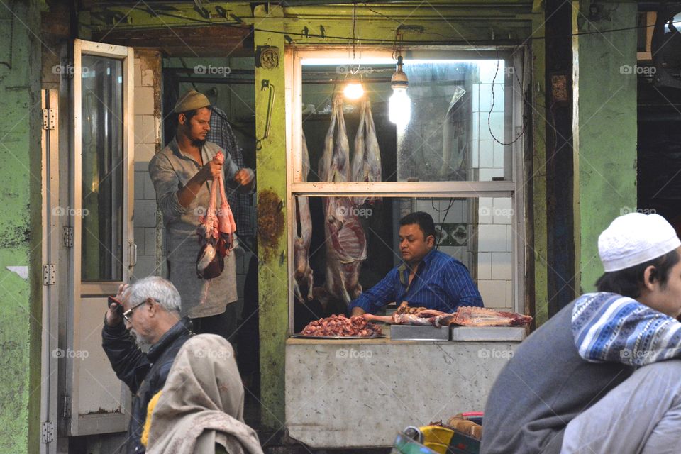 A shopkeeper selling raw lamb meat in his shop