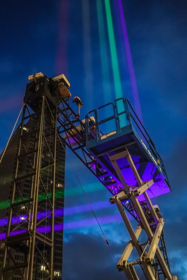 Looking up at the San Francisco Pride 2023 laser light installation of the scaffolding and lift that projected the Rainbow Pride Flag colors down Market Street towards Twin Peaks for 4.5 miles in the early evening as the lights began to glow 
