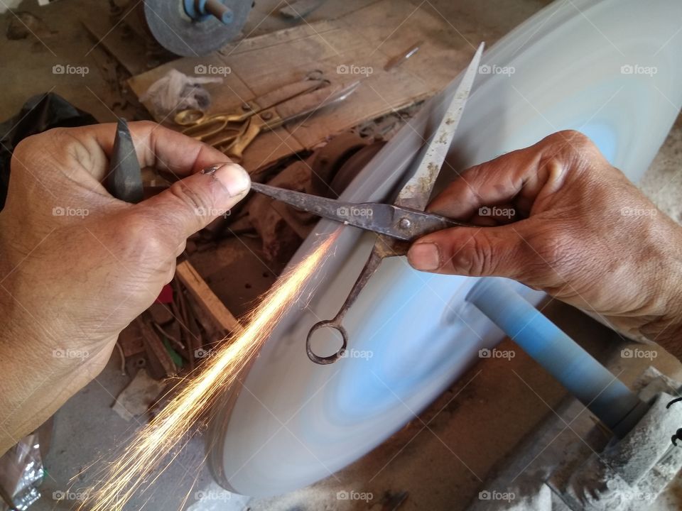 Close-up of man's hand sharpening scissors