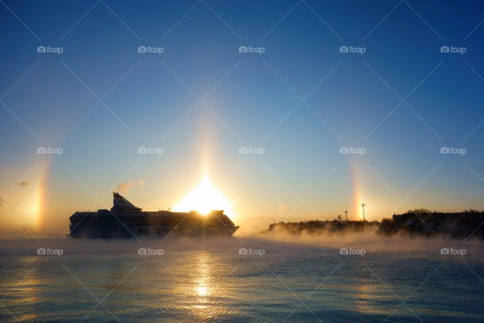 Ferry approaching Helsinki South harbor in freezing cold winter morning with morning mist in the Baltic Sea and strong halo in the sky on the background on 5 January 2016 in Helsinki, Finland.