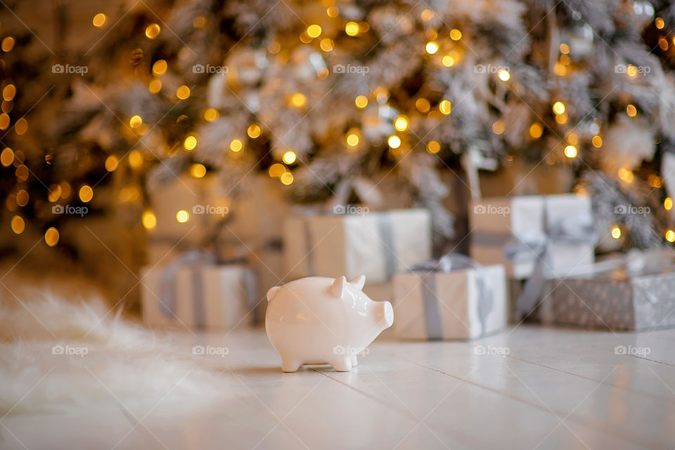 piggy bank with 100 dollars banknote in festive New Year atmosphere of scenery. Magical bokeh with Christmas tree and bright lights.