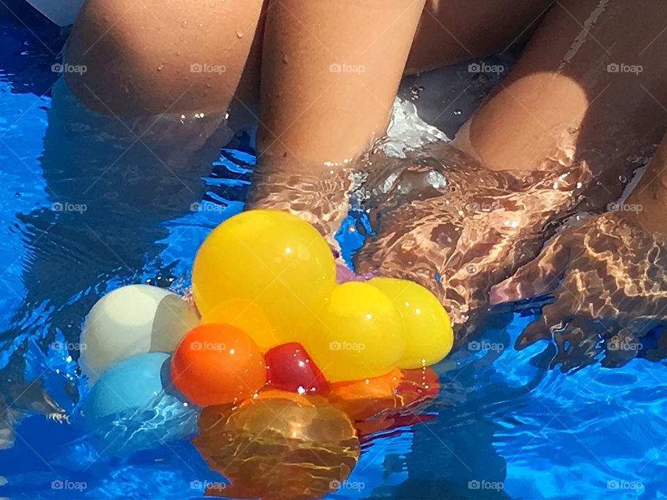 Children by the pool at play. Legs in the pool