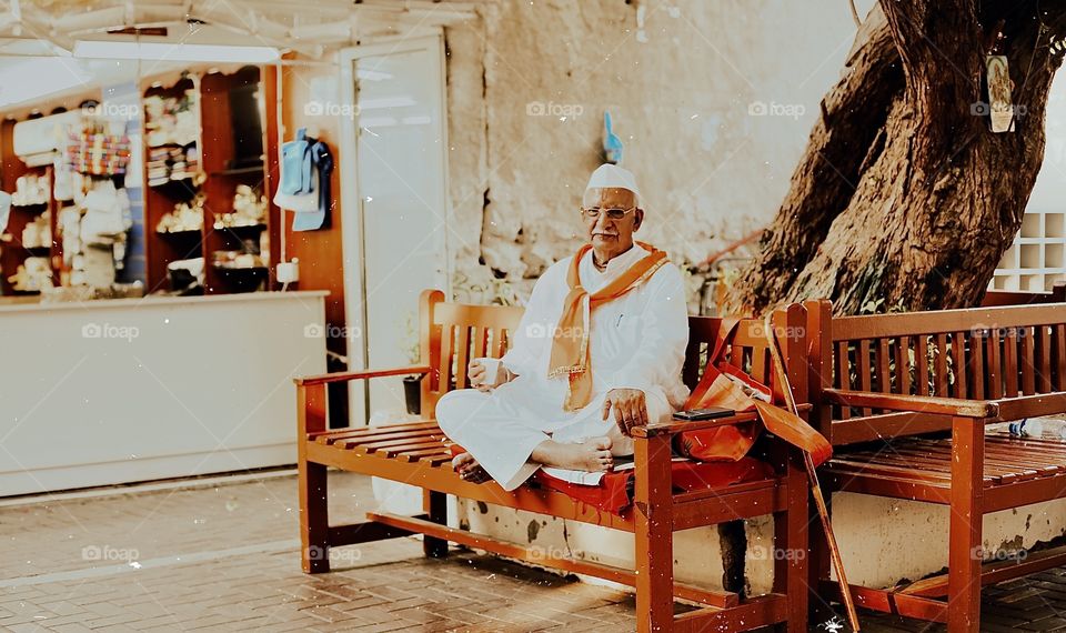 Old Indian Pakistani man seller have a break with tea at beach near his store 