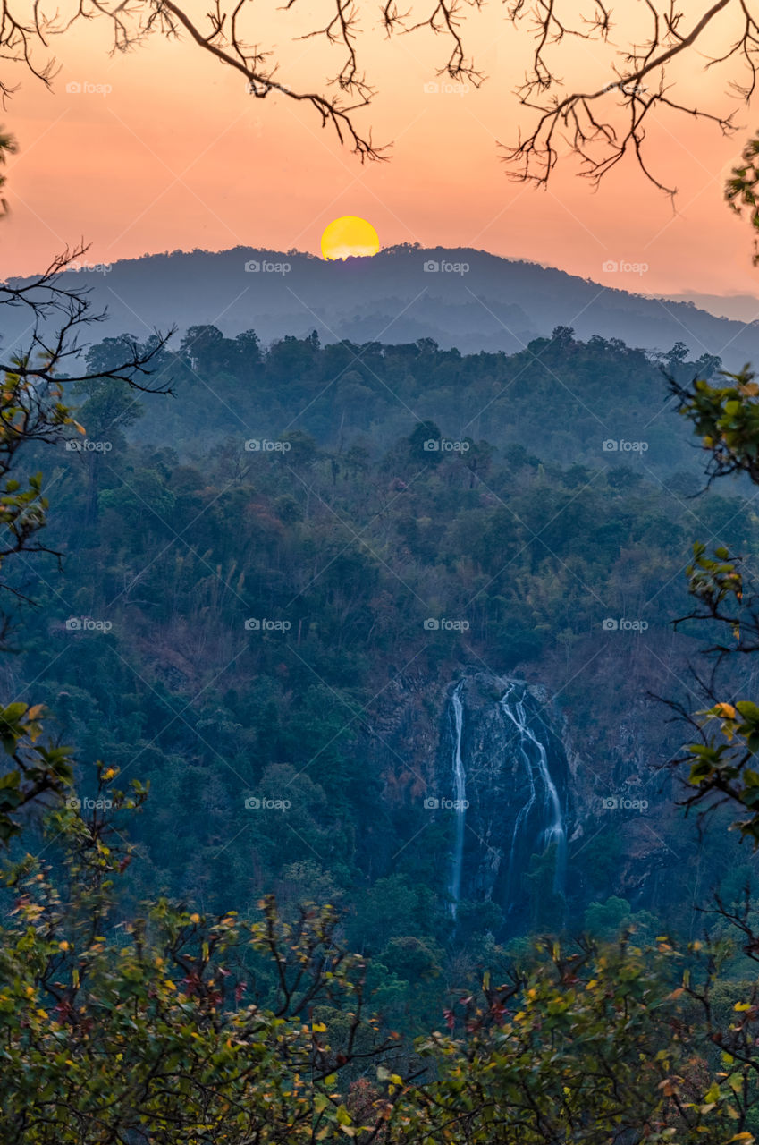 Beautiful sun set scene above waterfall in Thailand