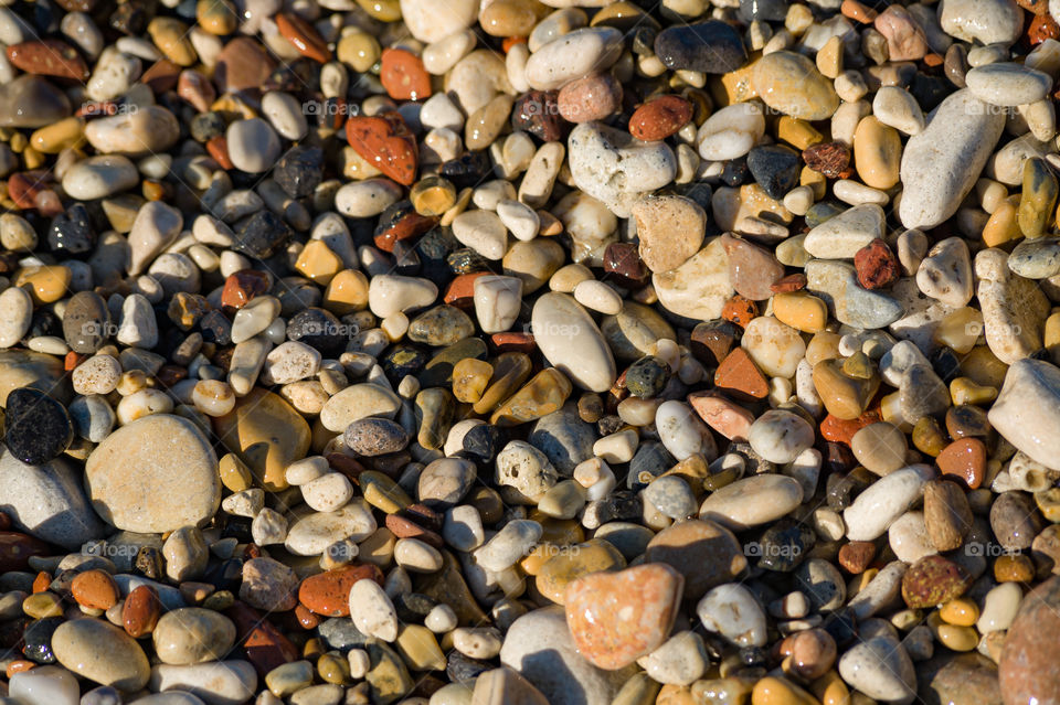 colored sea pebbles on the beach soaked in waves