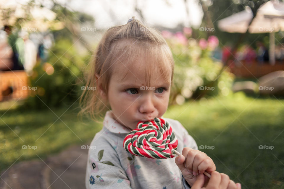 Little girl eating lollipop outdoor