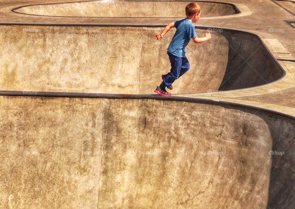 Love Running. Young Boy Running In A Concrete Expanse
