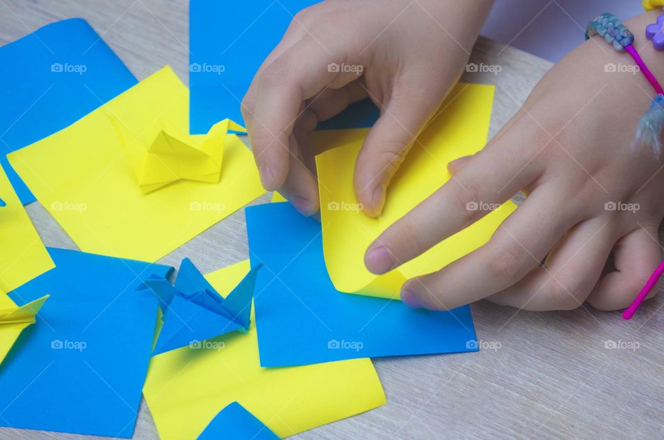 child folds paper cranes