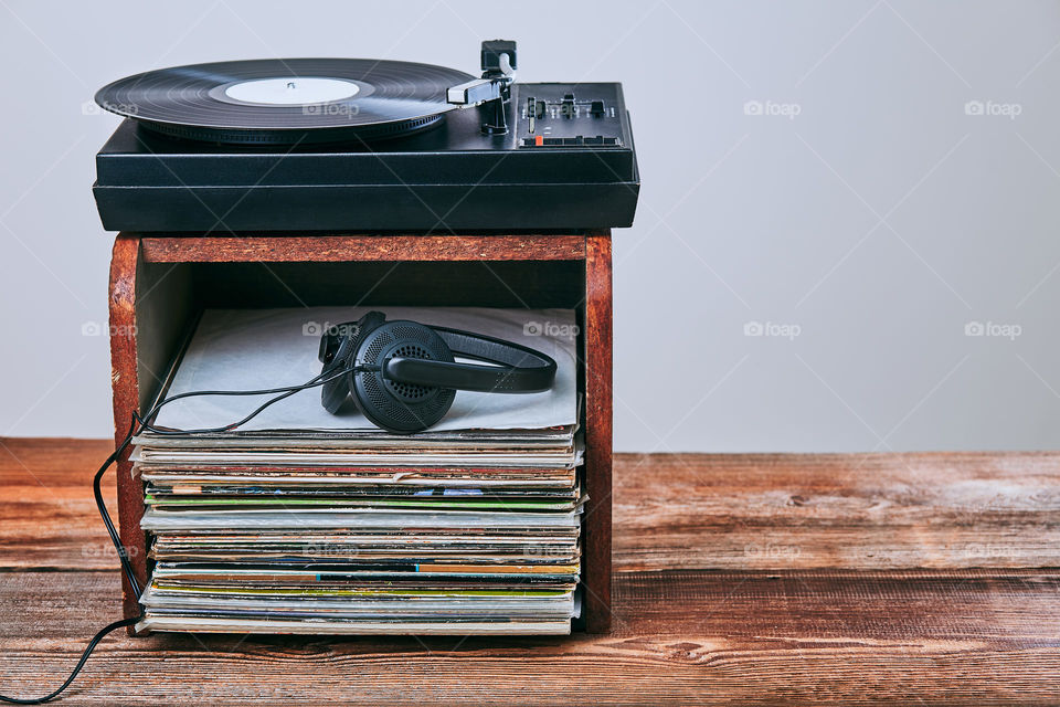 Stack of black vinyl records, turntable vinyl player and headphones. Classic stereo set. Candid people, real moments, authentic situations