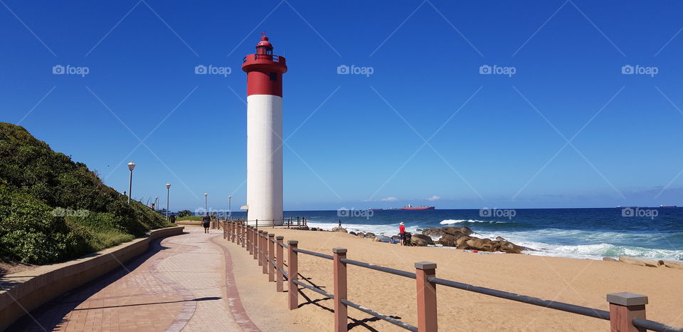 Promenade at Umhlanga Beach with its iconic red and white lighthouse on a perfect summer's day