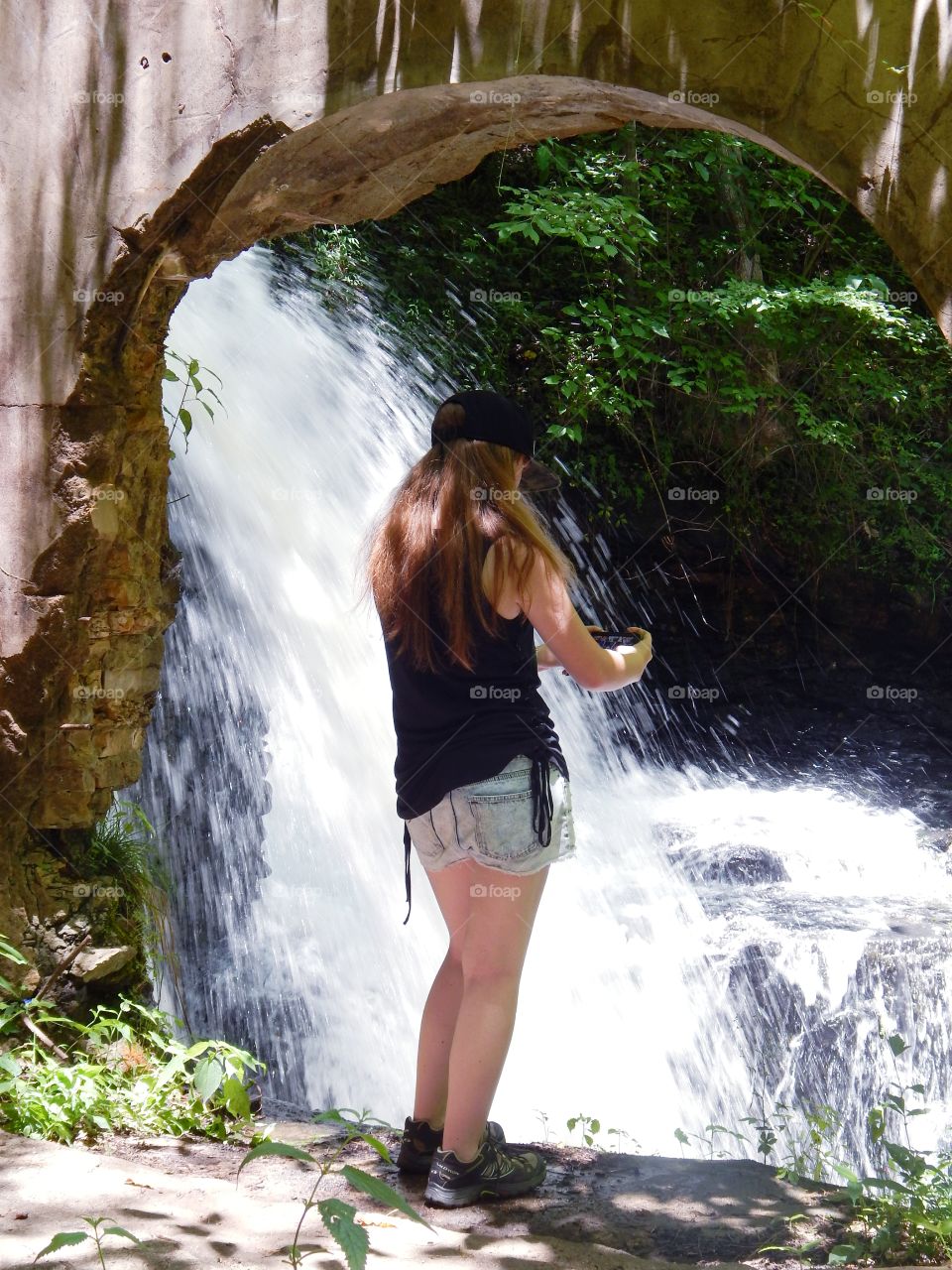 photo of girl standing in doorway of mill ruins taking photos of water fall at Watson mill state park