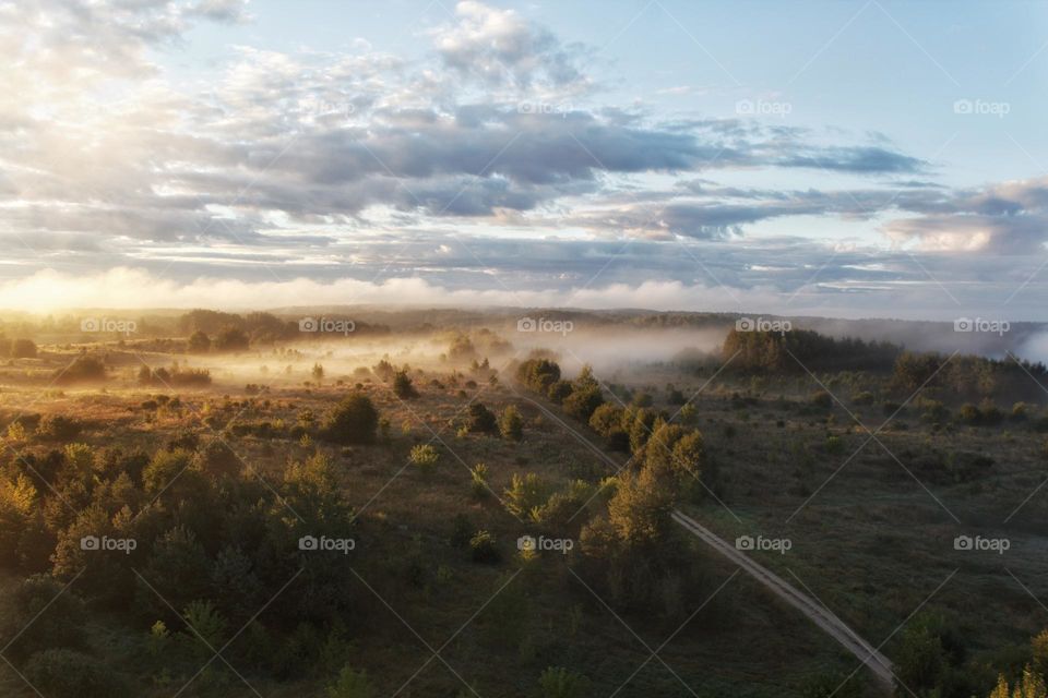 Hot air balloon ride over foggy autumnal road in Trakai, Lithuania.