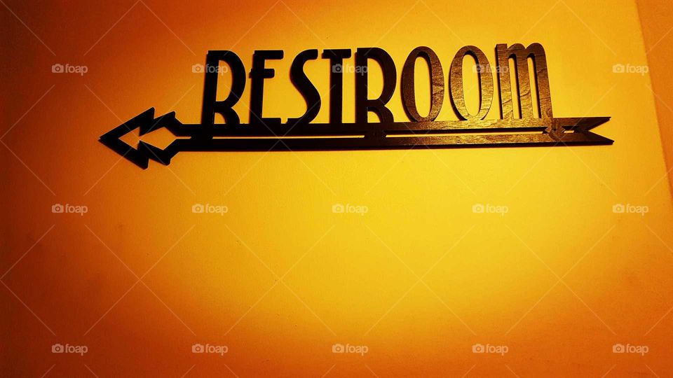 A Retro Restroom sign points the way on a yellow wall.