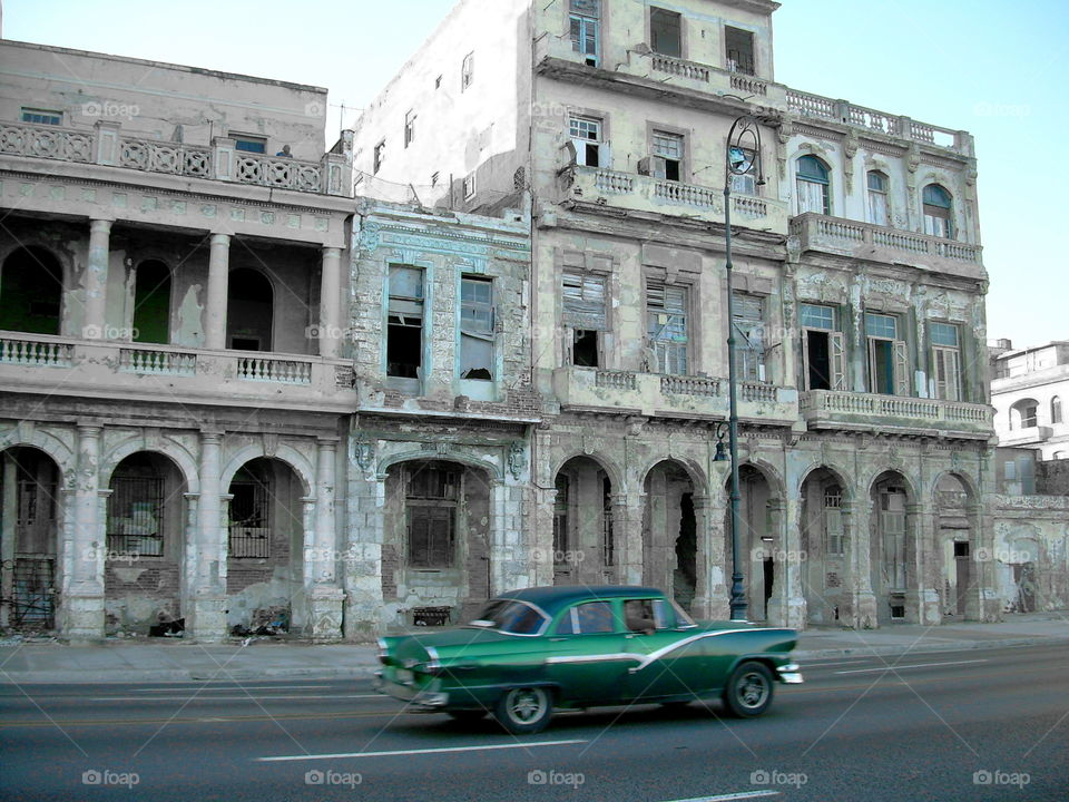 green vintage car on Malecon in old Havana Cuba with dilapidated houses in the background