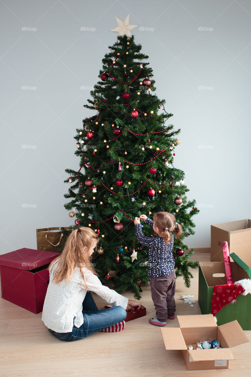 Mother and baby girl decorating christmas tree