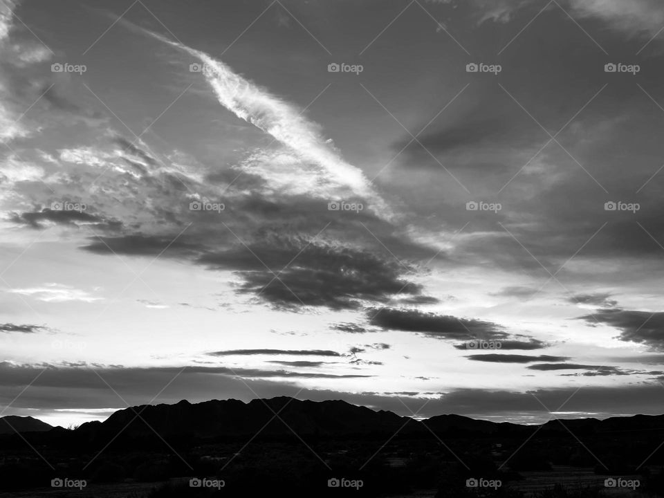 A black and white photo of a mountains with a cloudy sky above. 