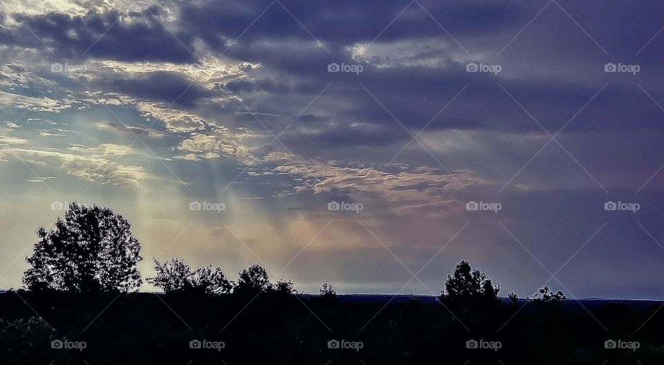 Heavenly sunlight shining through thick storm clouds.