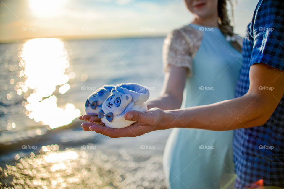 руки парня и девушки держат детские пинетки