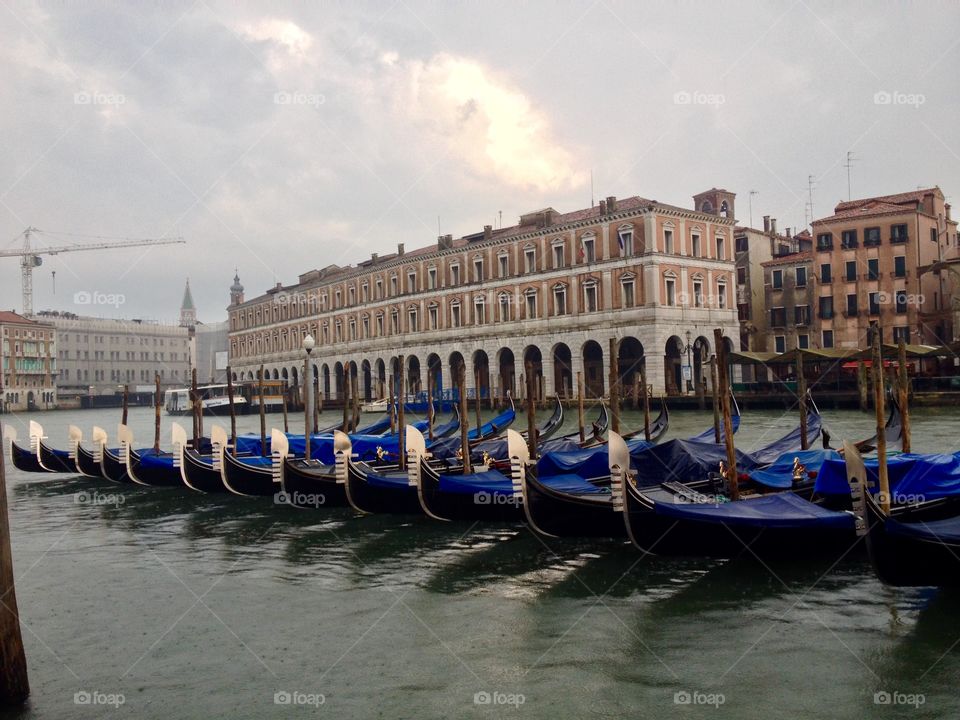 Covered gondolas and their reflections on a cloudy morning in Venice