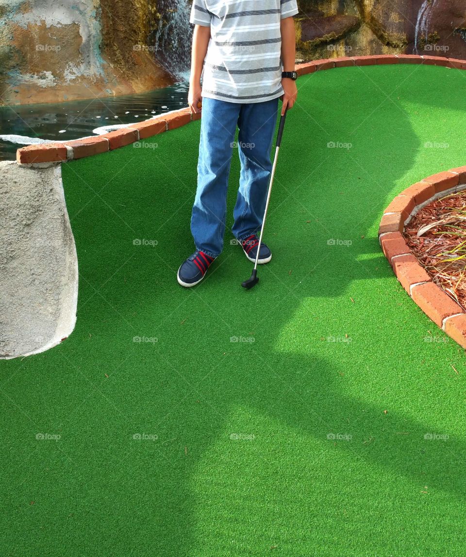 Boy playing mini golf