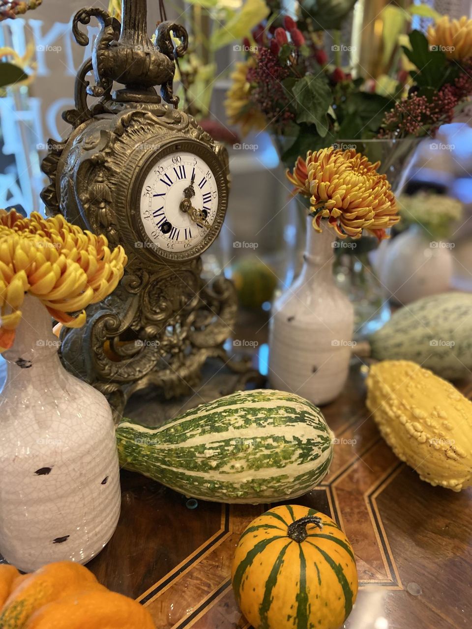 Antique clock, autumn flowers, and various pumpkins and squash inspiring warmth and love in the autumn season.