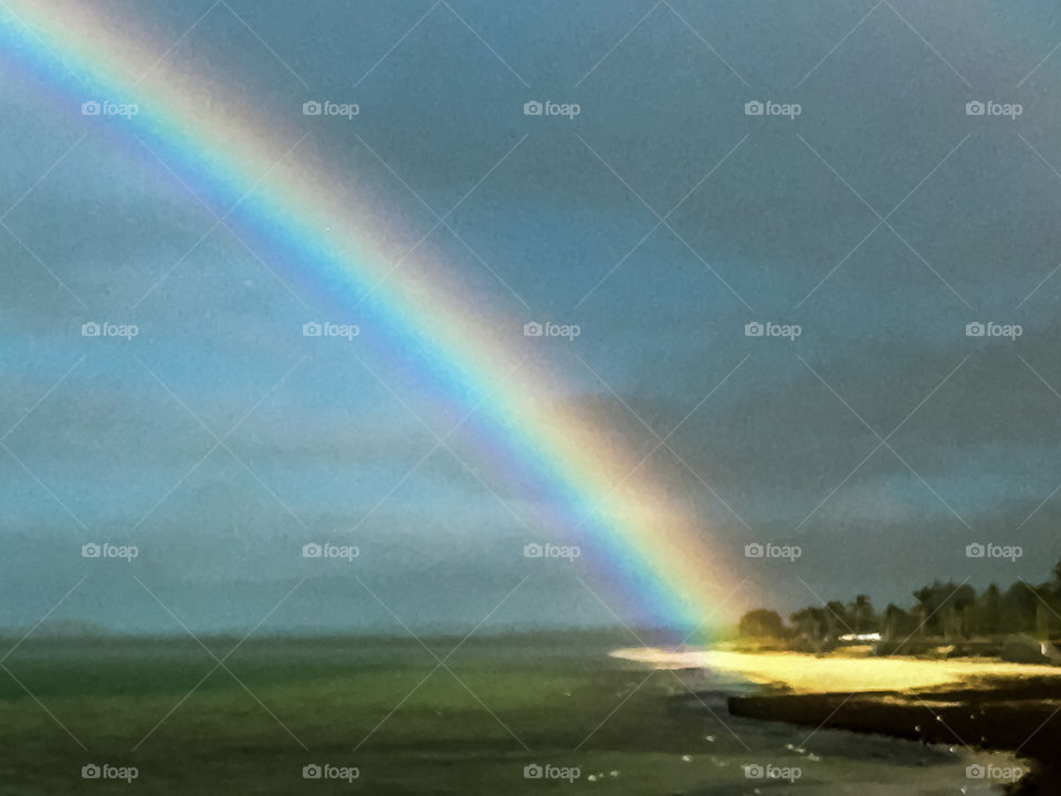 End of the rainbow, shining like a torch onto an area of the beach  in wintry south Australia 
