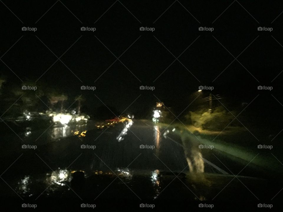 Rainy street in Florida, car headlights reflecting on wet pavement, road reflectors, with streetlight.