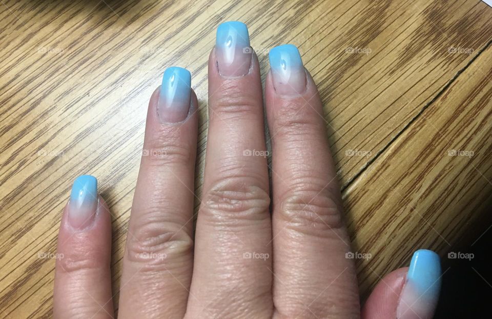Freshly manicured middle aged lady hand, with light blue and clear gel long nails