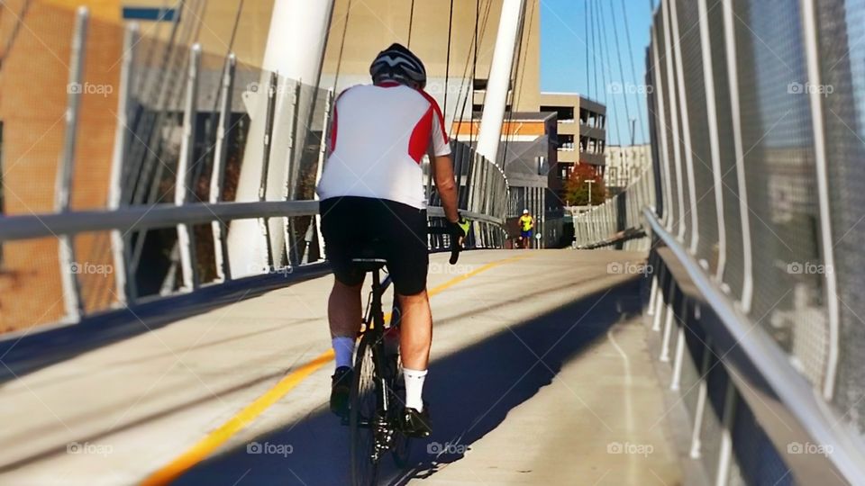 From A to B a man riding a bike and a woman running over an urban bridge in Dallas Texas