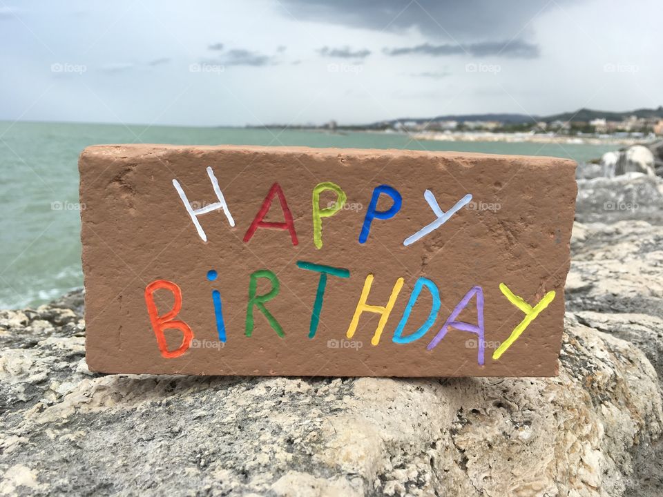 Happy Birthday, carved and colorful message on a brick